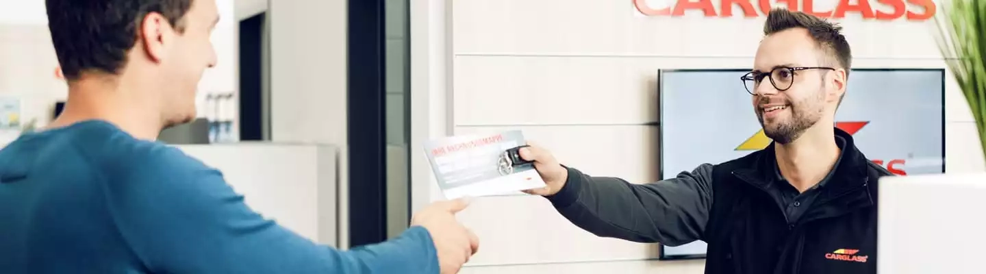 Mitarbeiter übergibt Dokumente und Autoschlüssel an Kunde