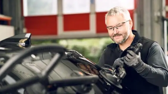 Monteur steht am Auto und richtet eine Heckscheibe aus um diese in das Auto einzusetzen