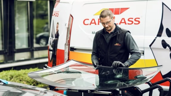 Monteur arbeitet im Freien, vor einem Transporter an einer Scheibe